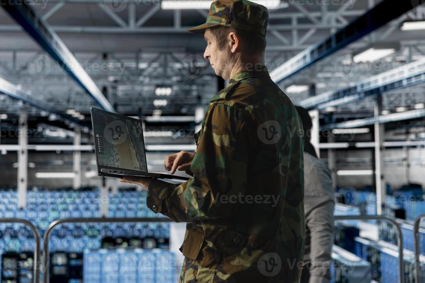 Military officer in data center monitoring warfare drone telemetry on laptop dashboard. IT specialist in army server hub using tactical interface on notebook to support aerial operations photo