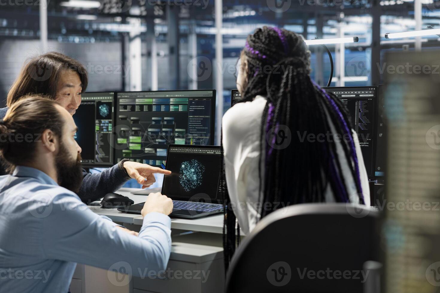 Team of admins in server room using devices to review infrastructure diagnostics. Teamworking IT staff members in data center analyzing performance data to maintain system uptime photo