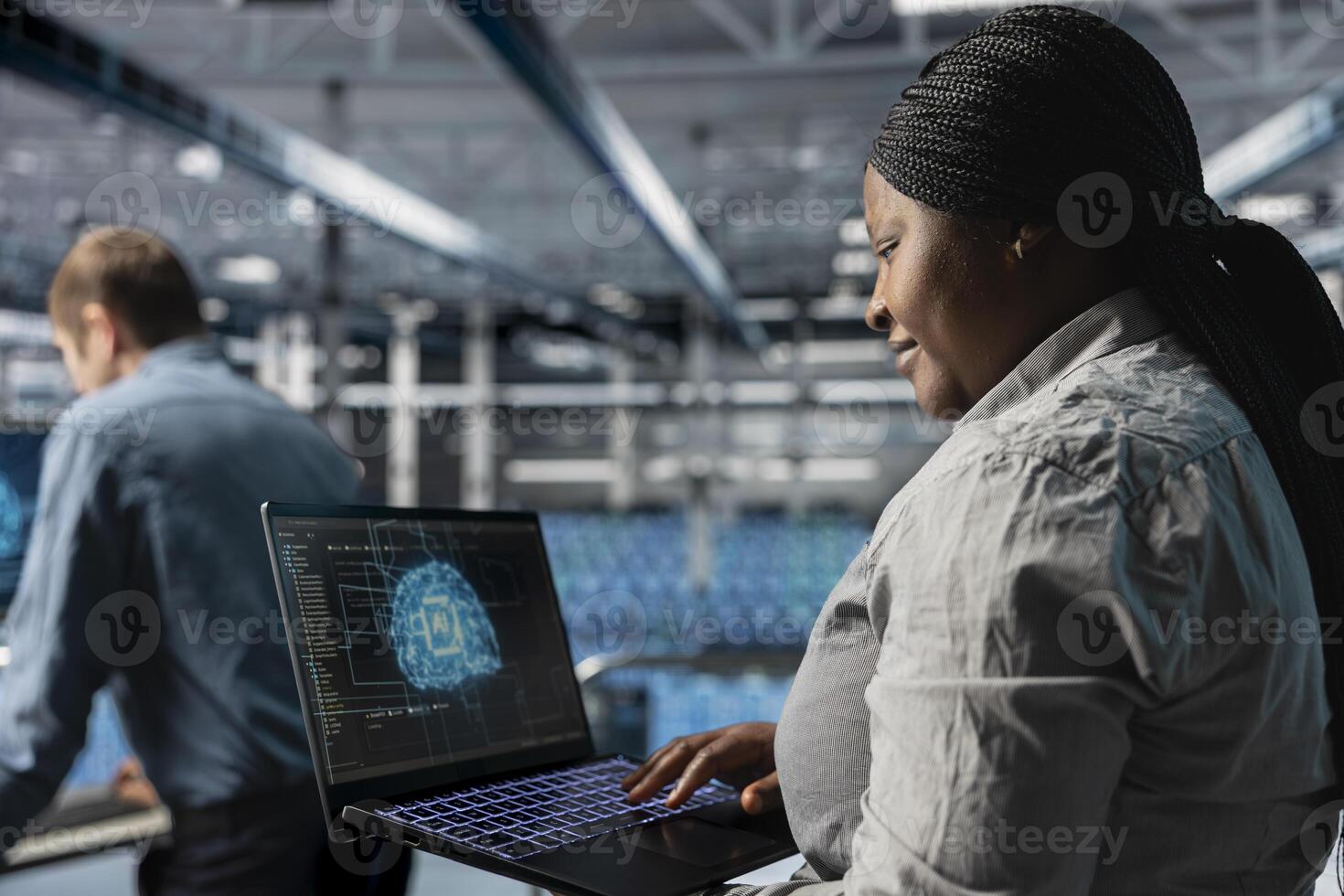 Smiling IT expert in server room using laptop to improve AI system scalability for increased workloads. Happy data center programmer using notebook to adjust artificial intelligence model parameters photo