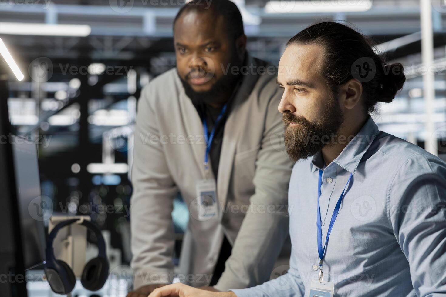 Team of technicians in data center using PC to update storage arrays software, configuring network virtualization. Teamworking colleagues in server room using computer to verify settings photo