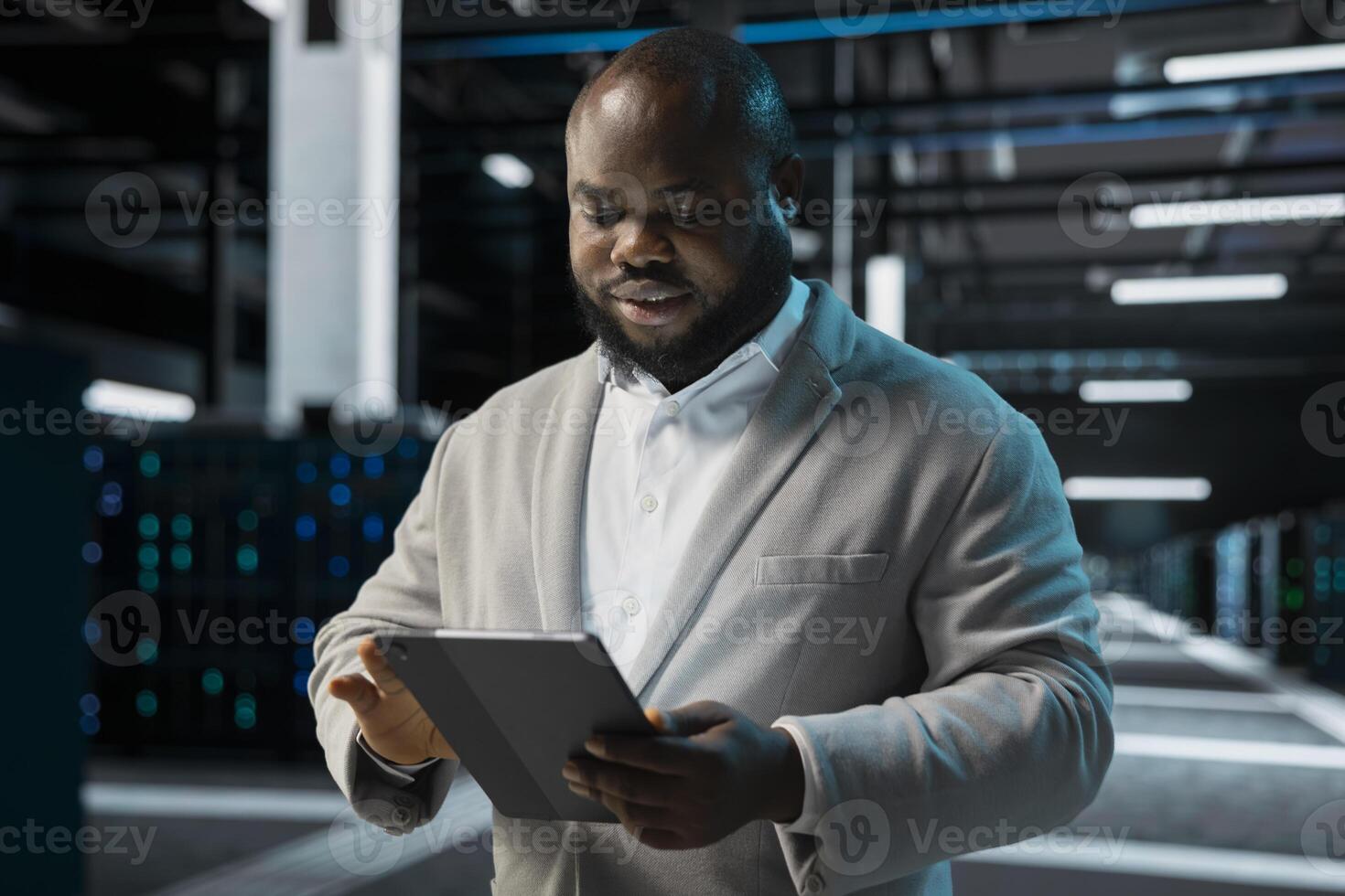 Engineer in server farm coordinating backups protocols, checking recovery plan. Data center IT specialist performing maintenance with tablet, making sure rigs are functioning optimally photo