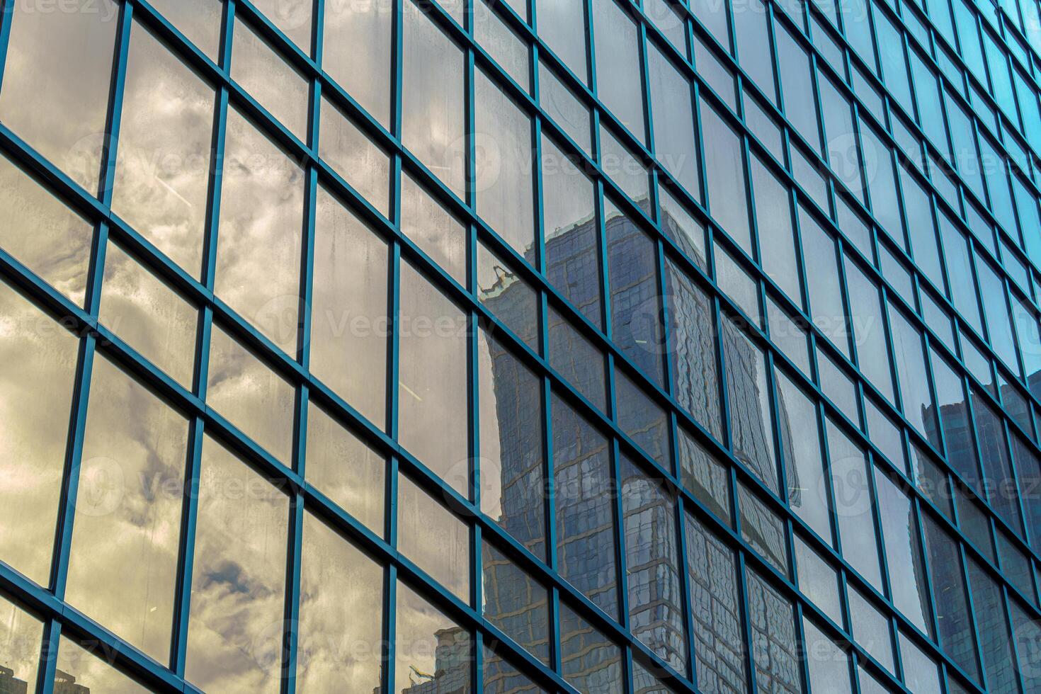 The reflection of a skyscraper and clouds in the glass panels of a building creates a captivating visual effect. photo