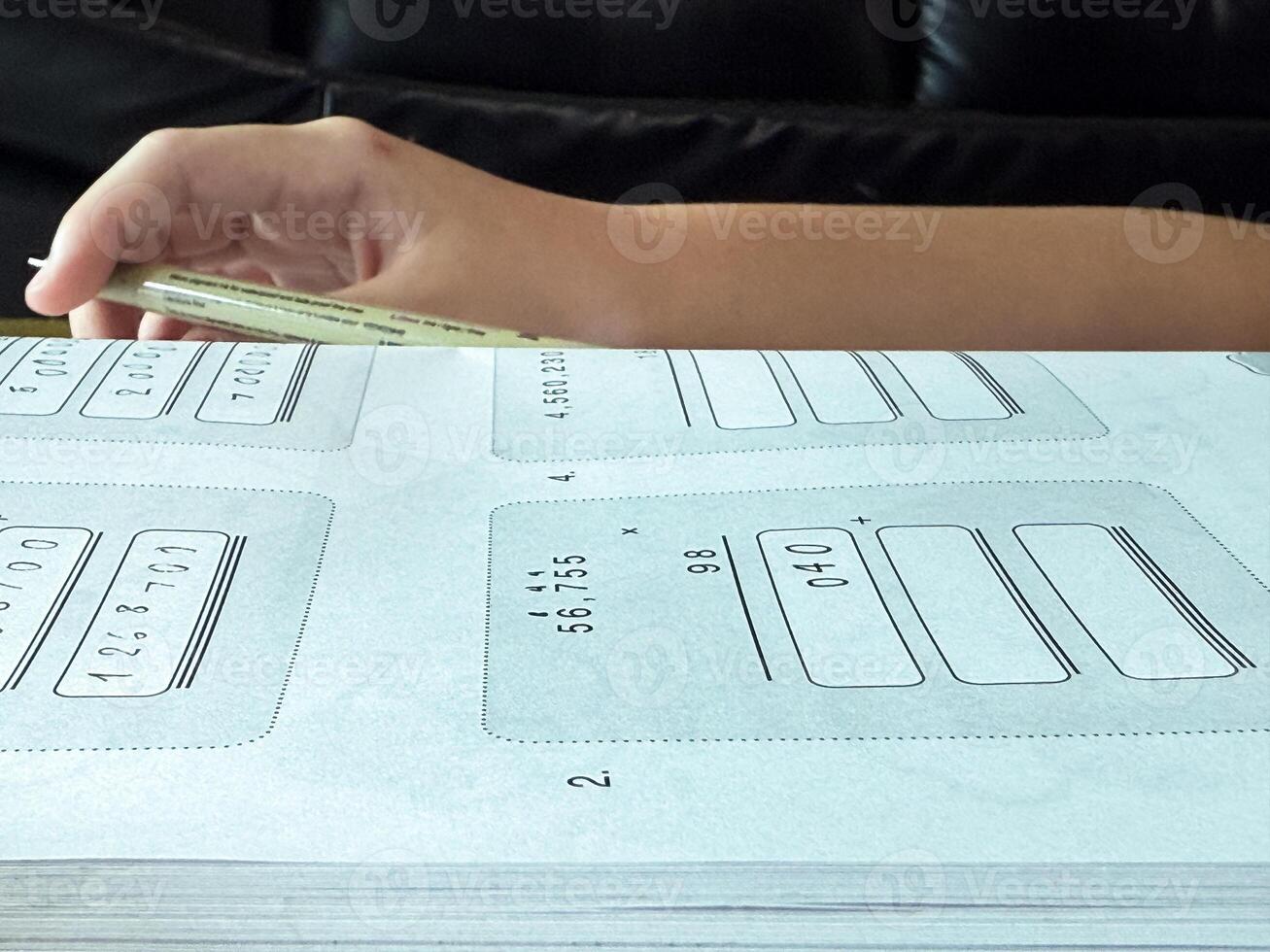 A young student sits at a wooden desk working on basic math exercises, steadily developing essential problem solving skills.b photo