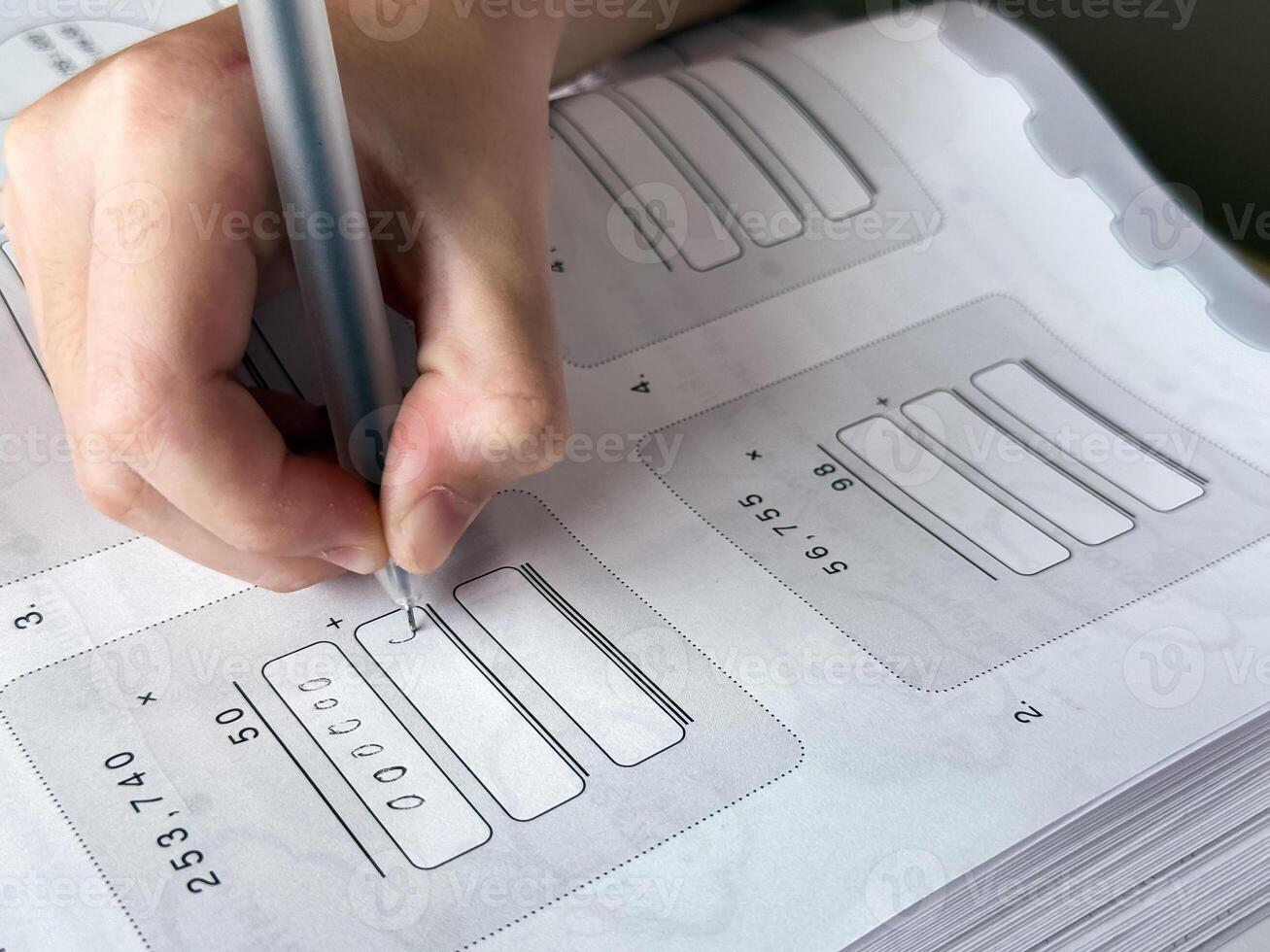 A young student sits at a wooden desk working on basic math exercises, steadily developing essential problem solving skills.g photo