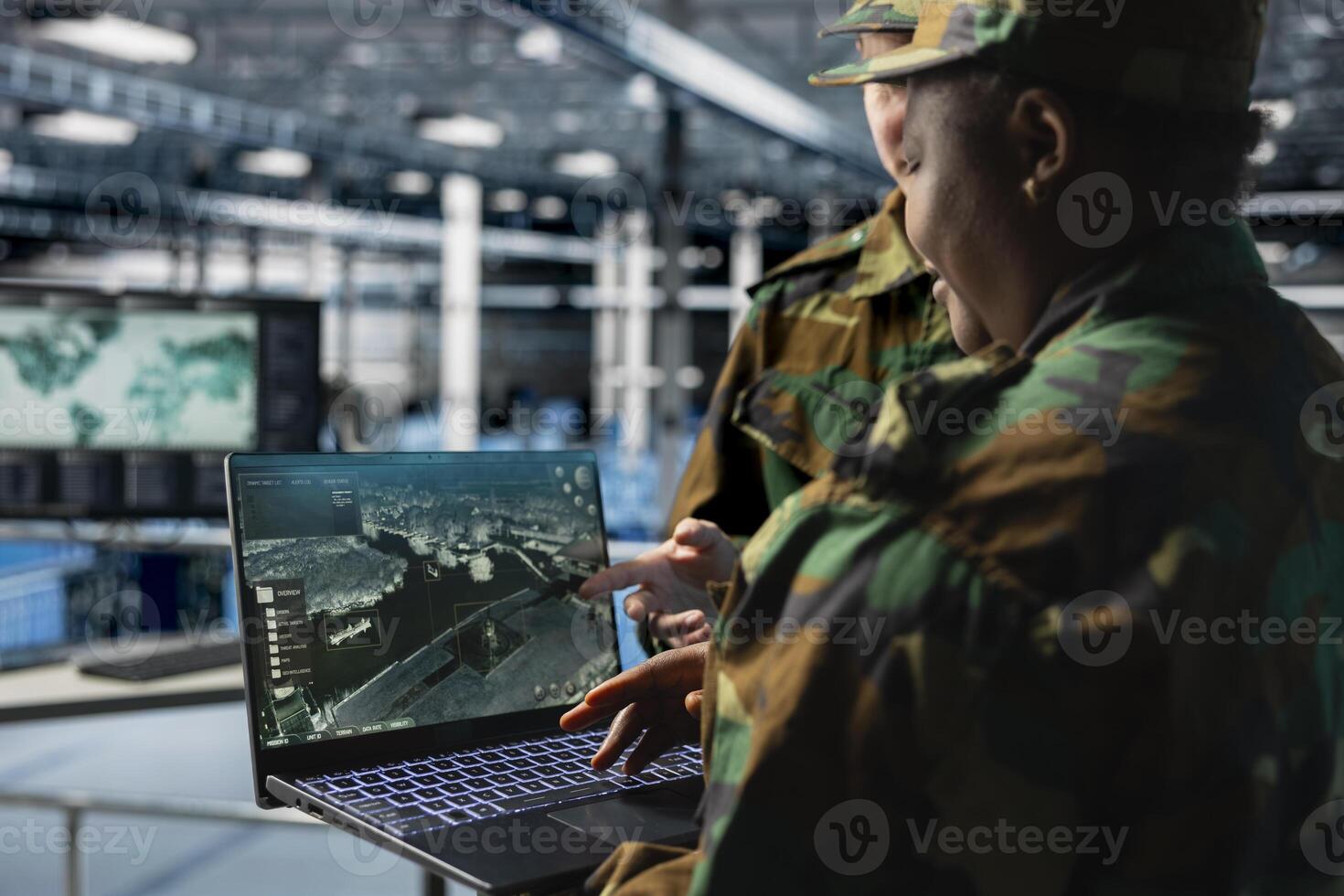 Team of army experts in data center reviewing satellite intelligence feeds on laptop. Military units in server farm command center supporting battlefield strategy with orbital imaging analysis photo