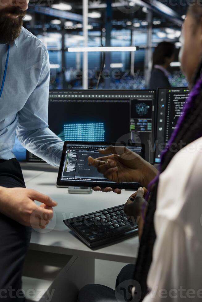 Close up of computer scientists coding on tablet in data center, updating AI automation scripts. Coworkers in server room programming artificial intelligence algorithms, debugging rigs photo