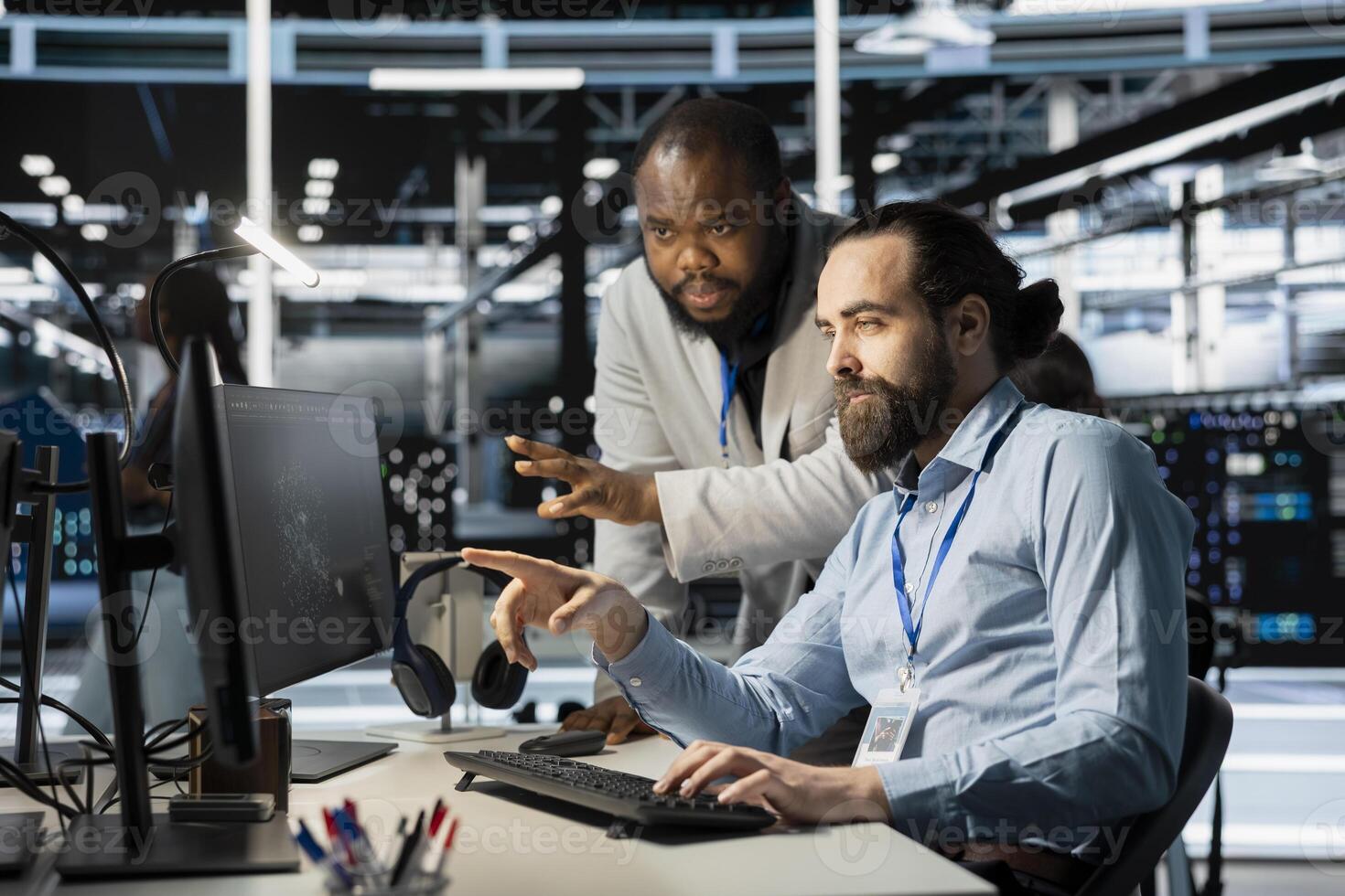 Team of system administrators using computer in server farm, analyzing data. Data center office colleagues doing brainstorming, examining equipment, ensuring system integrity and security photo