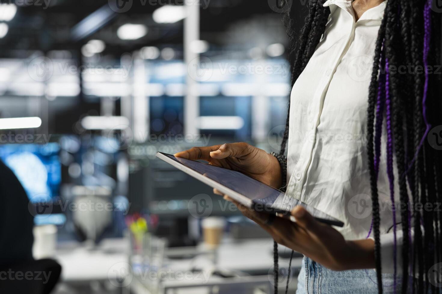 Close up of data center engineer using tablet, deploying and maintaining server and network hardware. Server hub employee using device to manage large scale IT infrastructure photo