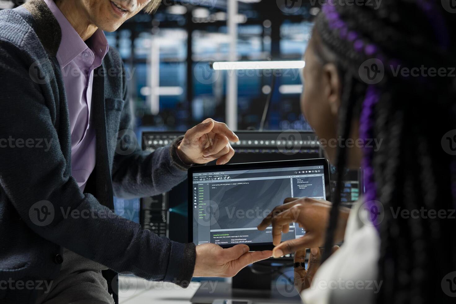 Close up of programmers coding on tablet in data center, updating AI driven automation scripts. IT workers using device in server room, programming artificial intelligence algorithms, debugging gear photo