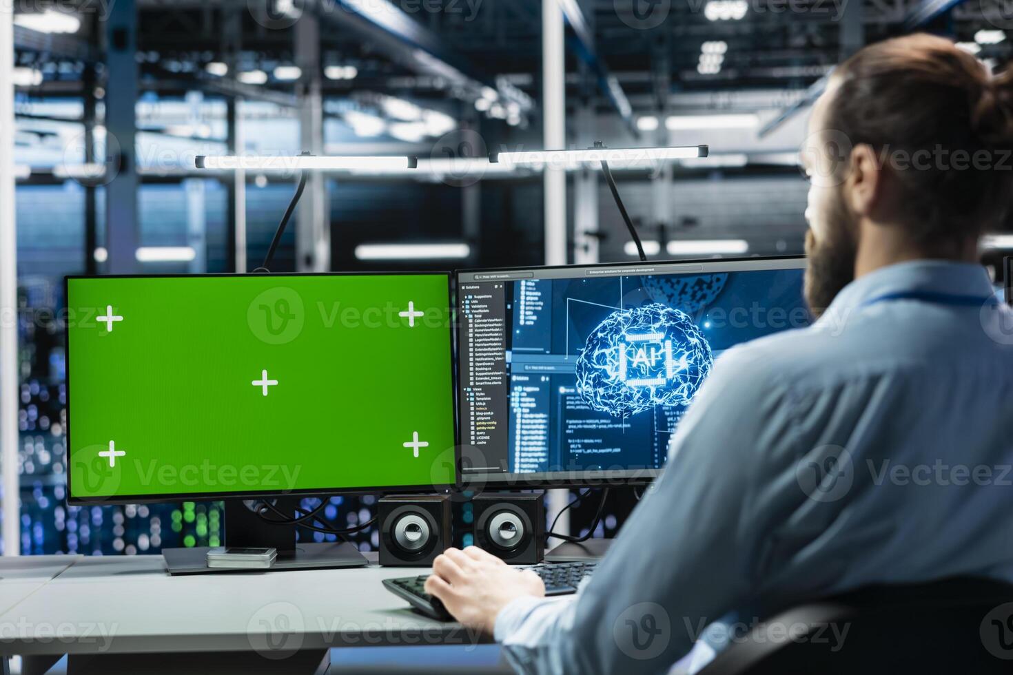 Engineer in data center managing AI training datasets using isolated screen PC monitor. Man using mockup PC display to oversee machine learning in server room supporting scalable infrastructure for AI apps photo