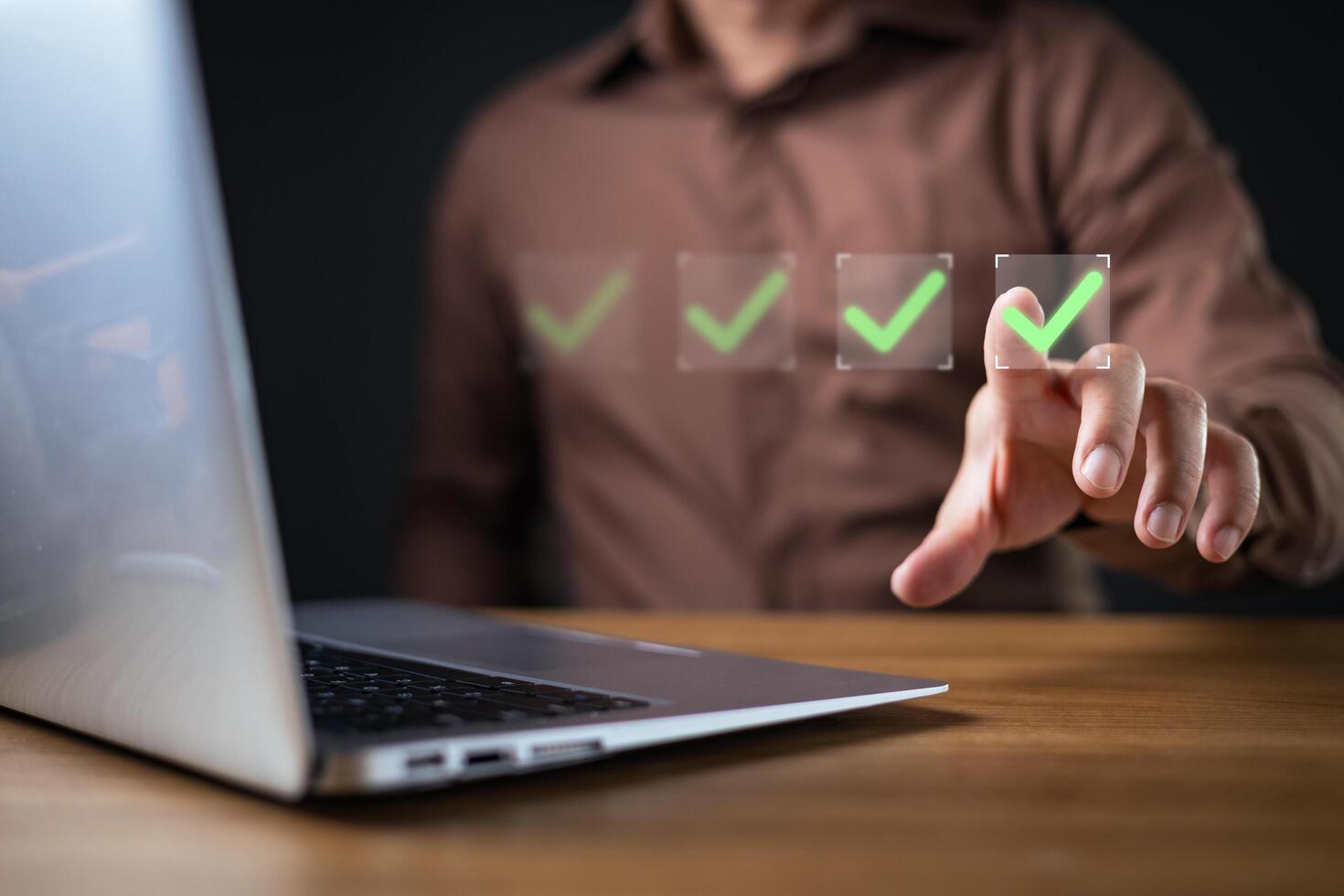 A person interacts with a laptop while selecting green check marks on a virtual checklist, representing document approval, task control, and efficient questionnaire completion in a digital workflow. photo