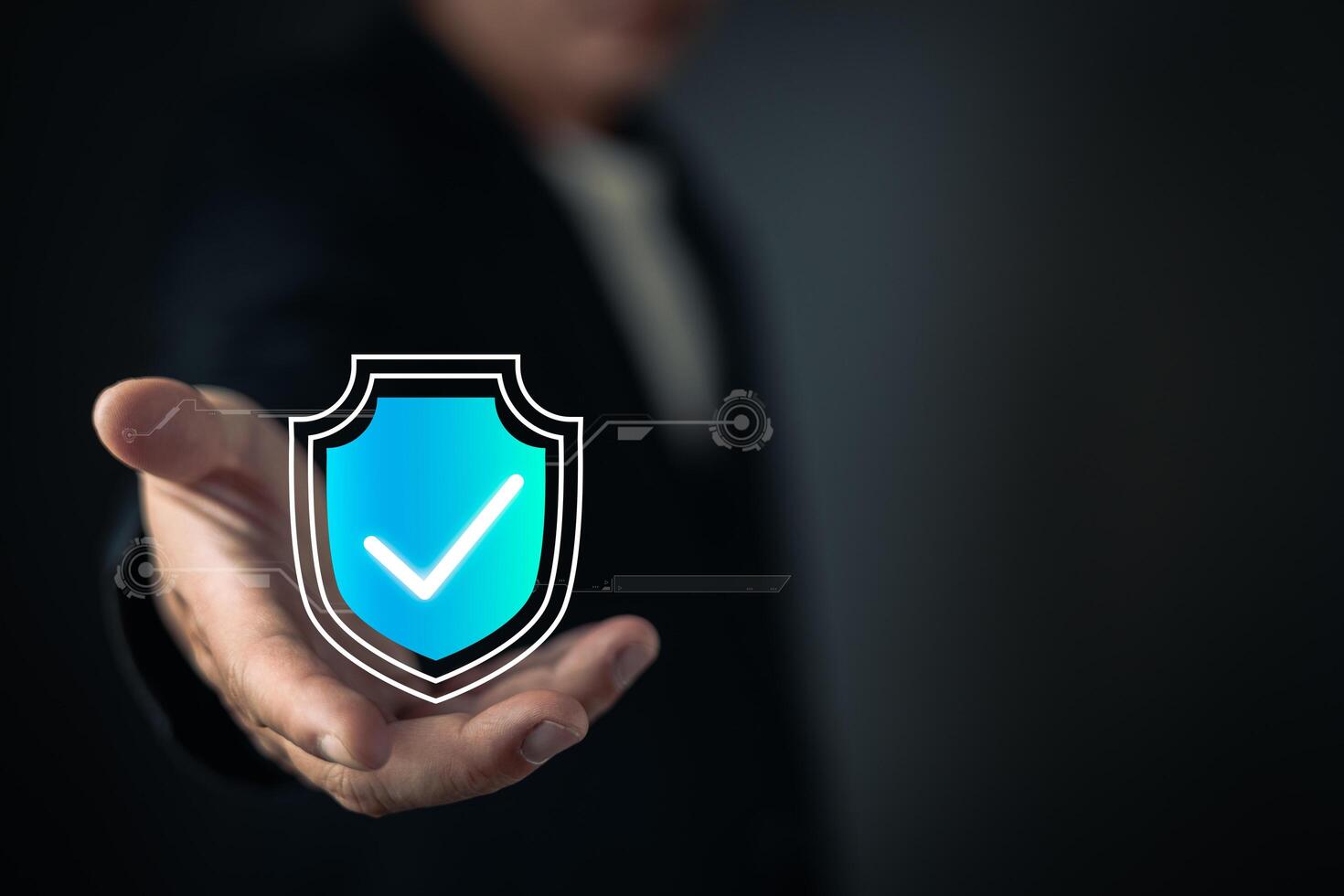 A person extends their hand, showcasing a glowing blue shield icon with a checkmark, symbolizing cyber security, data protection, trust, and secure digital systems in a modern technological context. photo