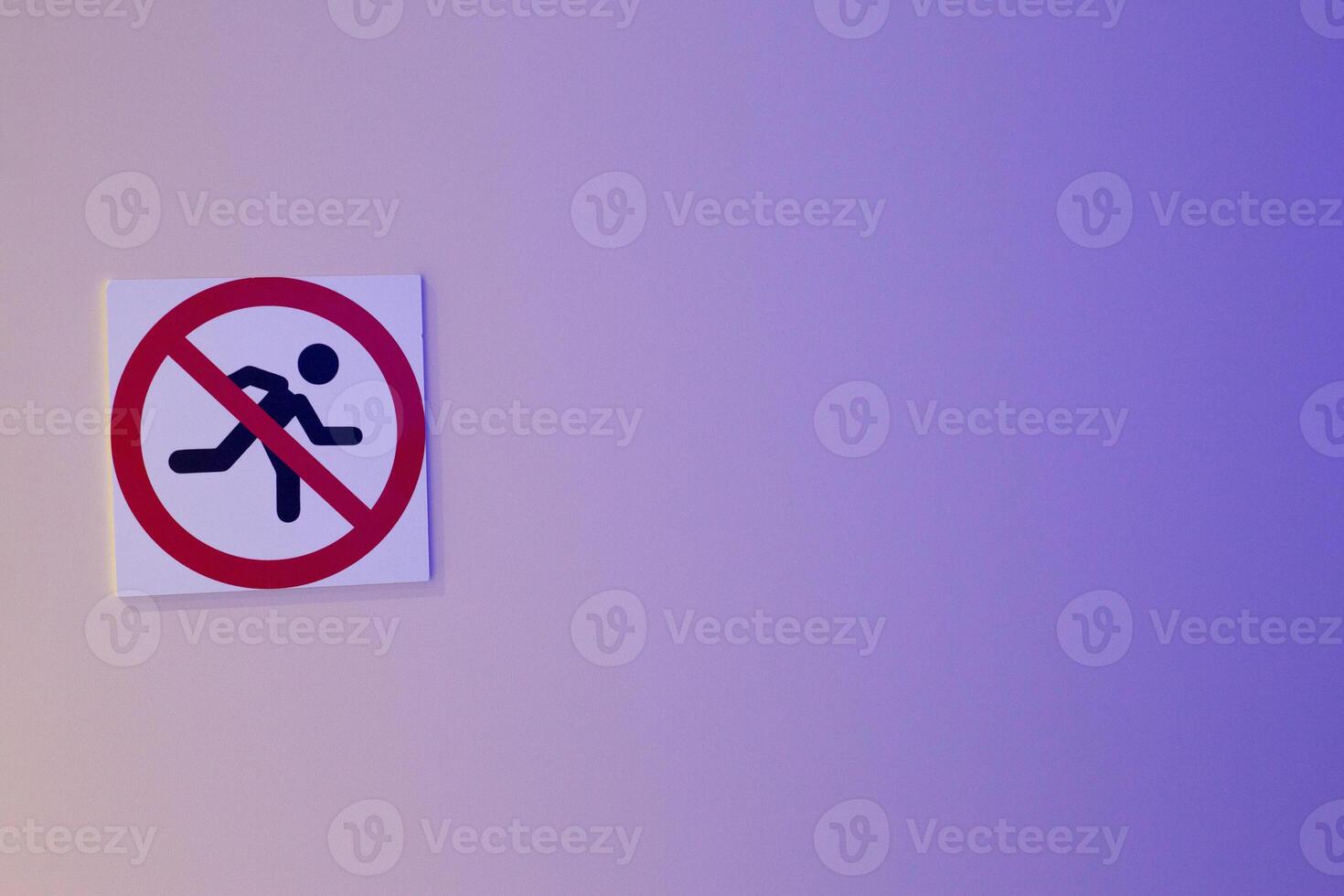 No running sign on light blue background. The symbol shows person running crossed out with red circle, enforce safety regulations in areas where running is prohibited photo