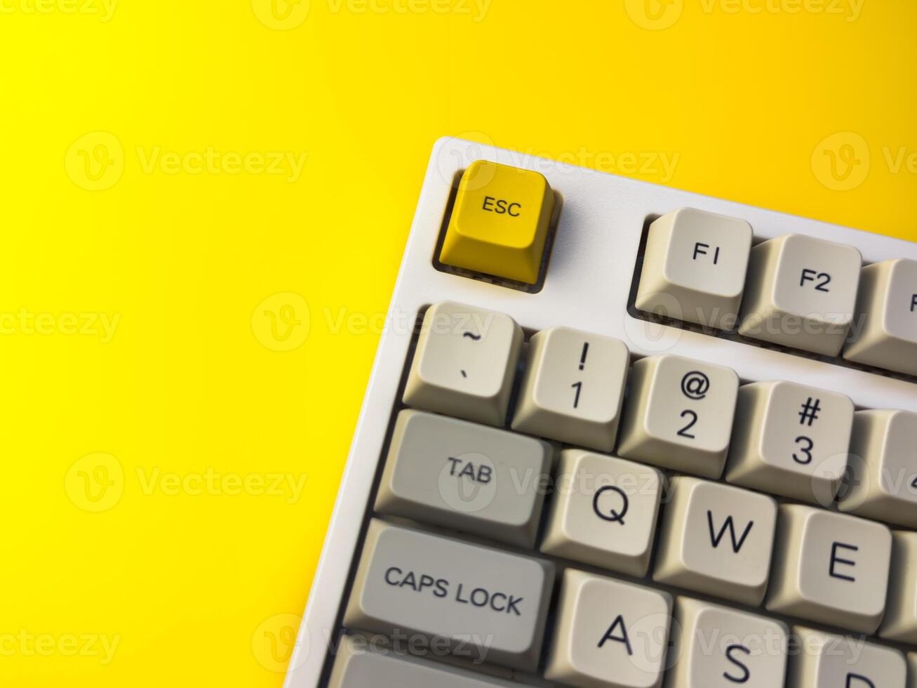bright Esc key on bright yellow background, minimalism, keyboard buttons. A keyboard with a yellow key on the bottom left photo