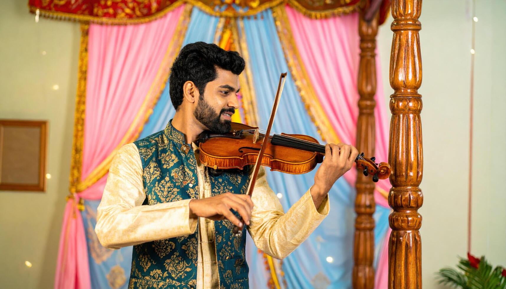 Man playing violin at festive event with colorful drapes and decorative background, expressing joy and concentration, creating lively and cultural atmosphere photo