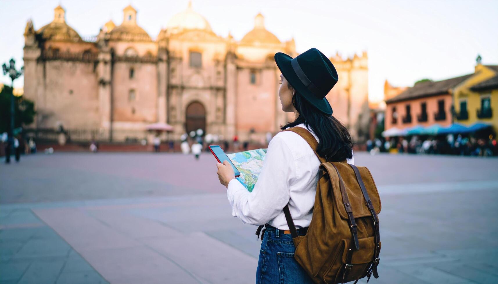 Woman with backpack looking map and using smartphone historic city square during daytime, capturing essence of travel and exploration with scenic background of old architecture and vibrant photo