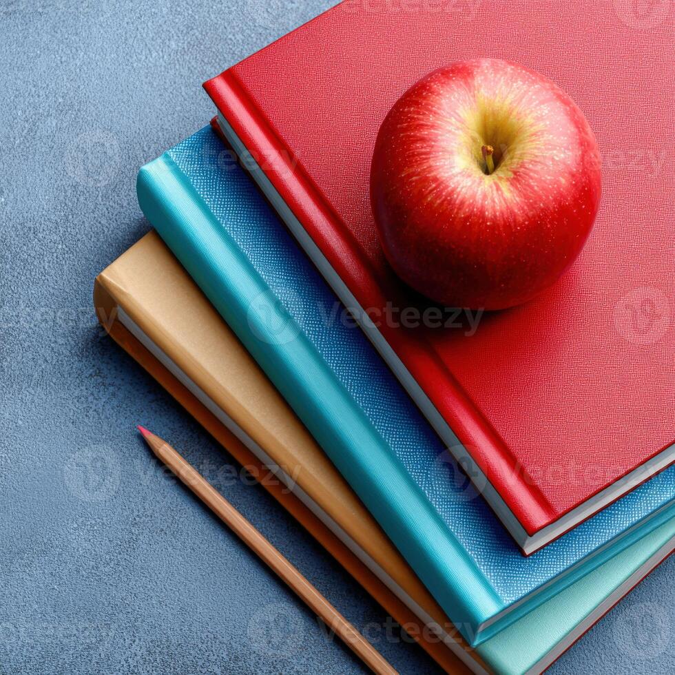 A red apple sits on top of a stack of books photo