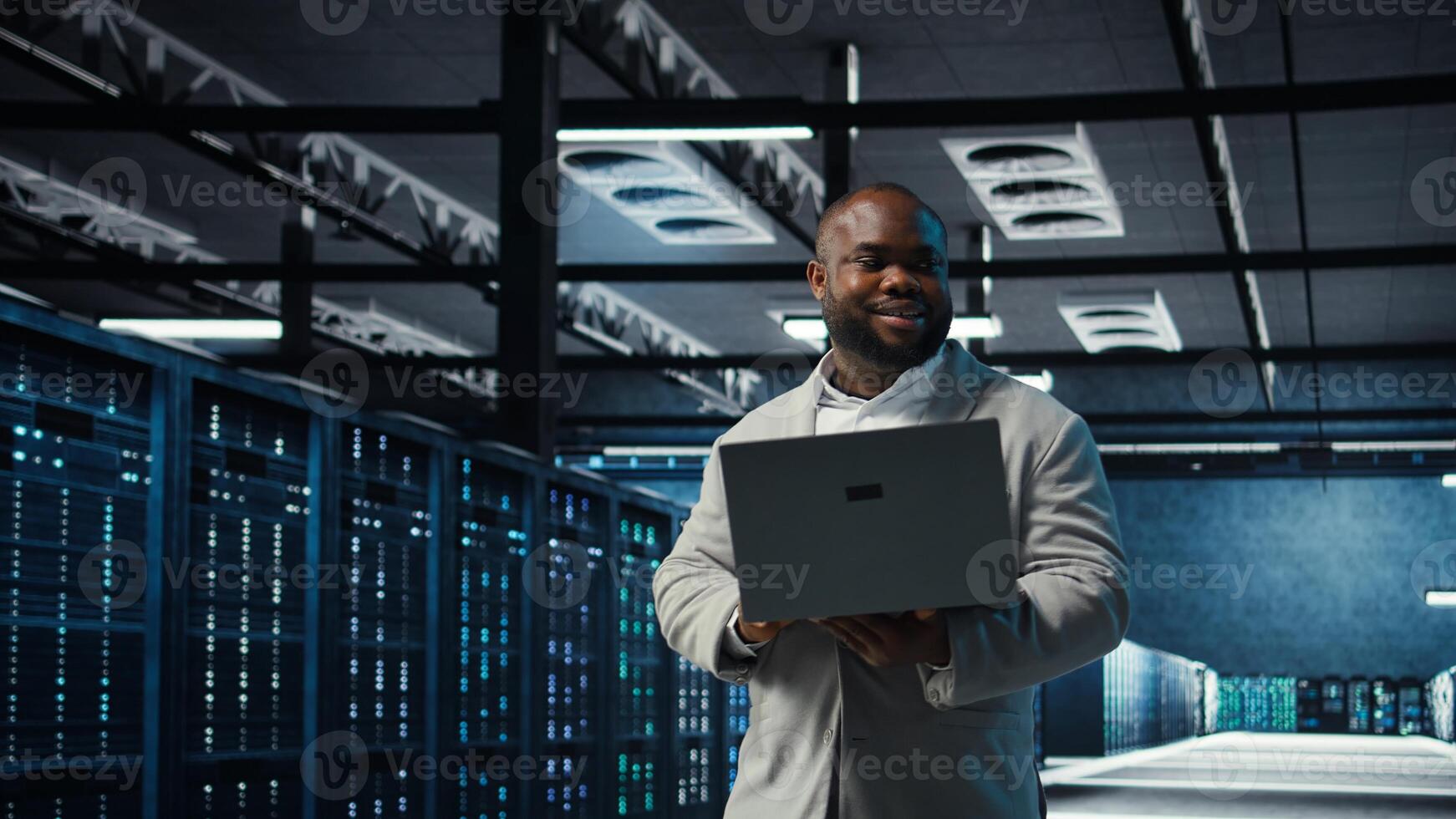 Engineer walking in data center using AI automation during maintenance session. African american server hub worker configuring deep learning models in hardware rigs, camera A photo