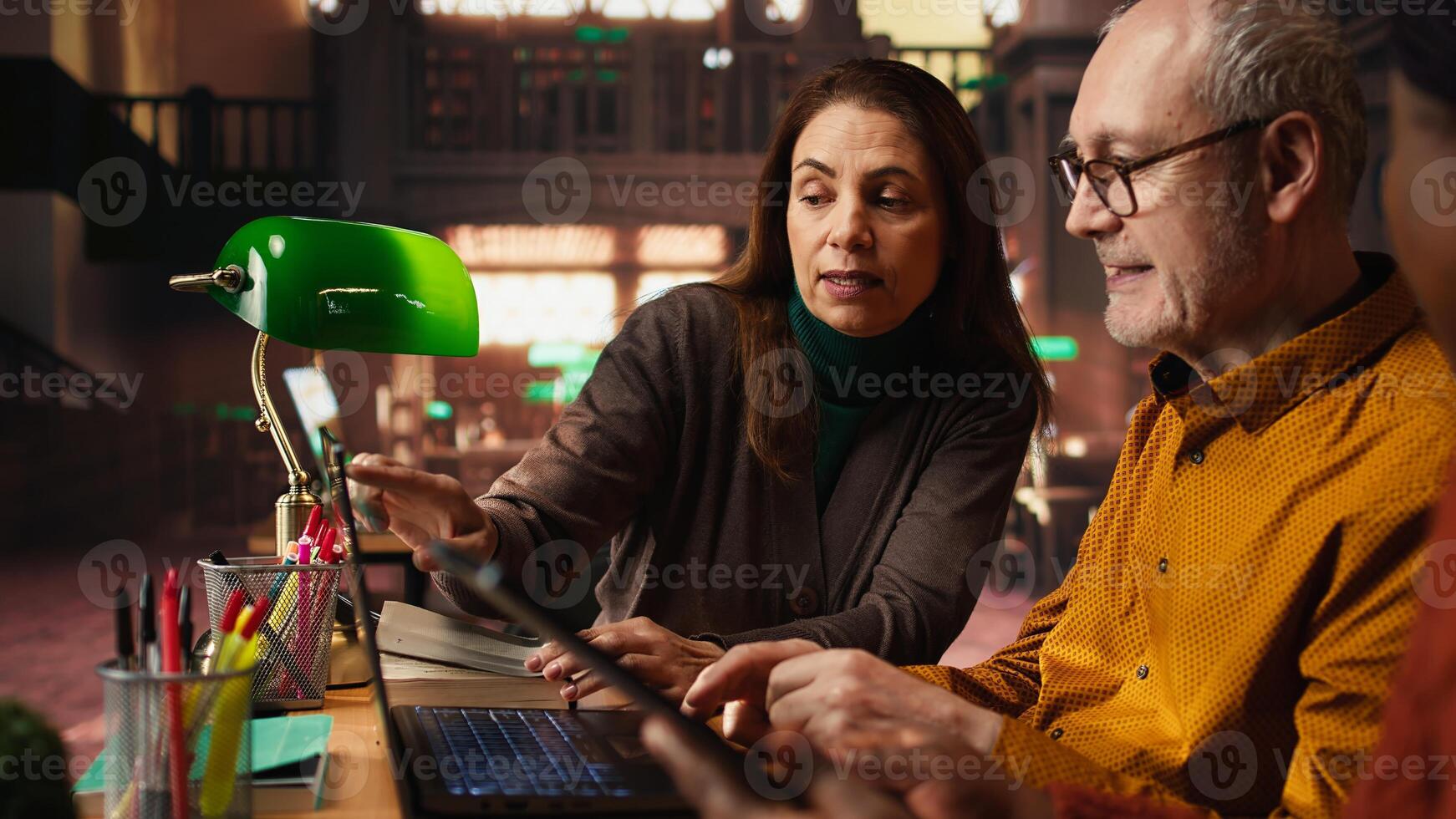Multiethnic colleagues team writing class notes at the library, studying and reading in the college campus. Working together on learning and preparing for their diploma thesis. photo