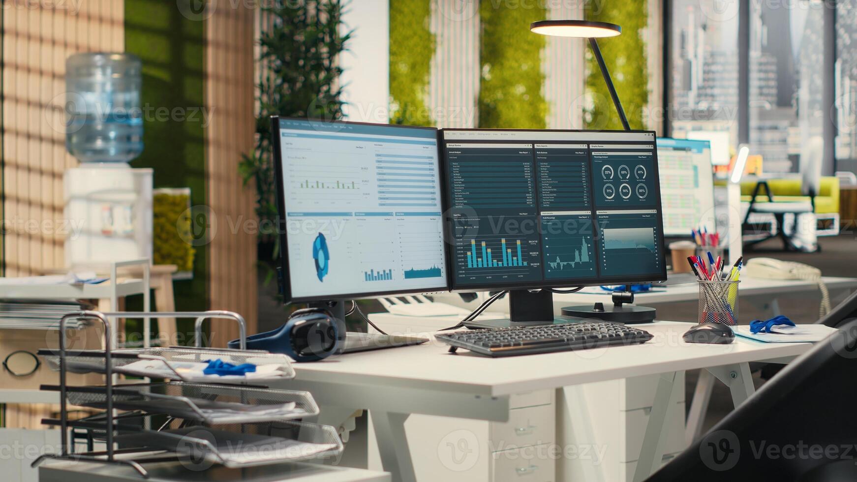 Empty business offices with dual monitors running financial diagnostics to help planning development strategy, data analytics and performance metrics. efficiency at the workspace. photo