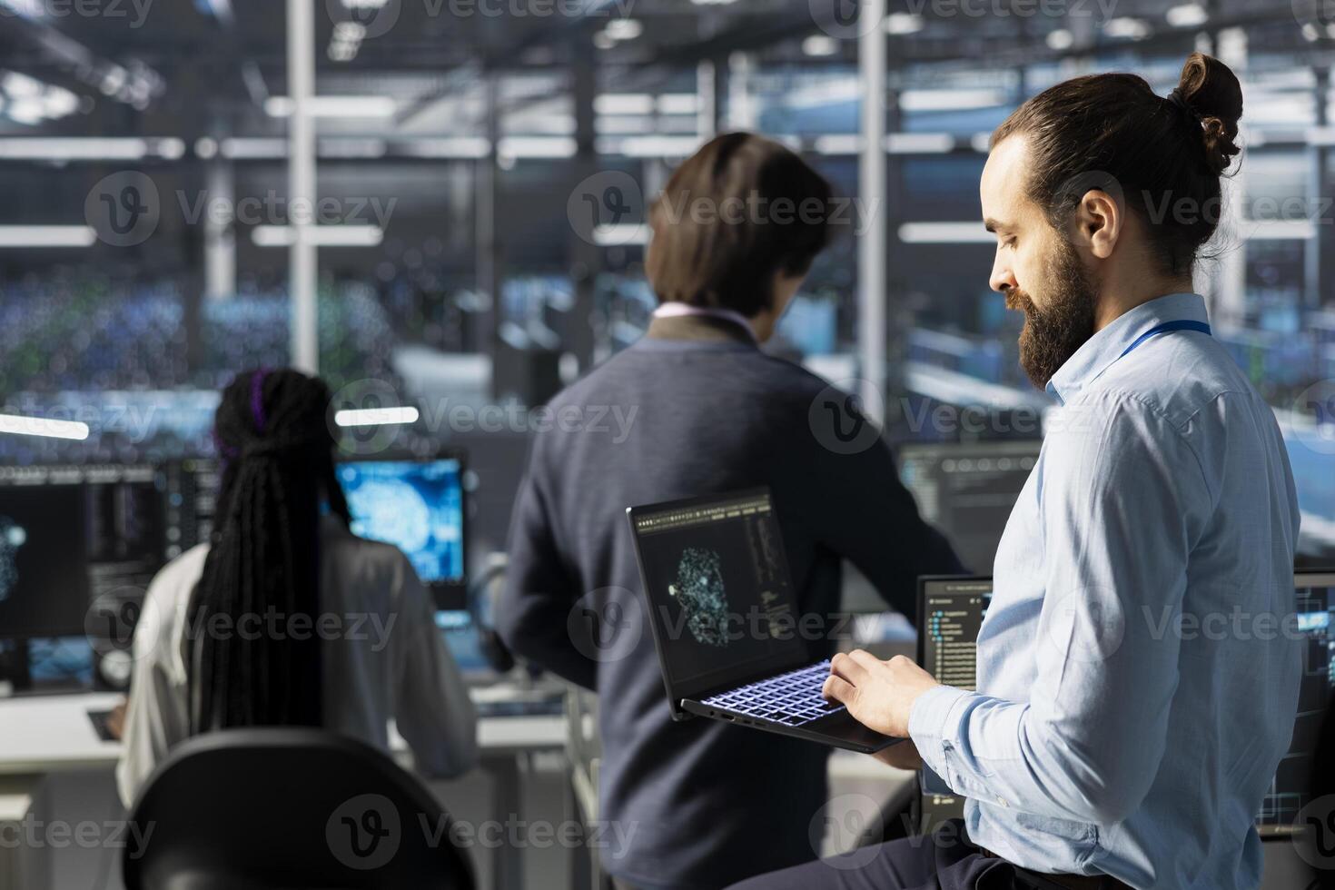 Engineer using laptop in data center with gear managing AI training datasets. IT expert using notebook, overseeing deep learning gear in server hub supporting scalable infrastructure for AI apps photo
