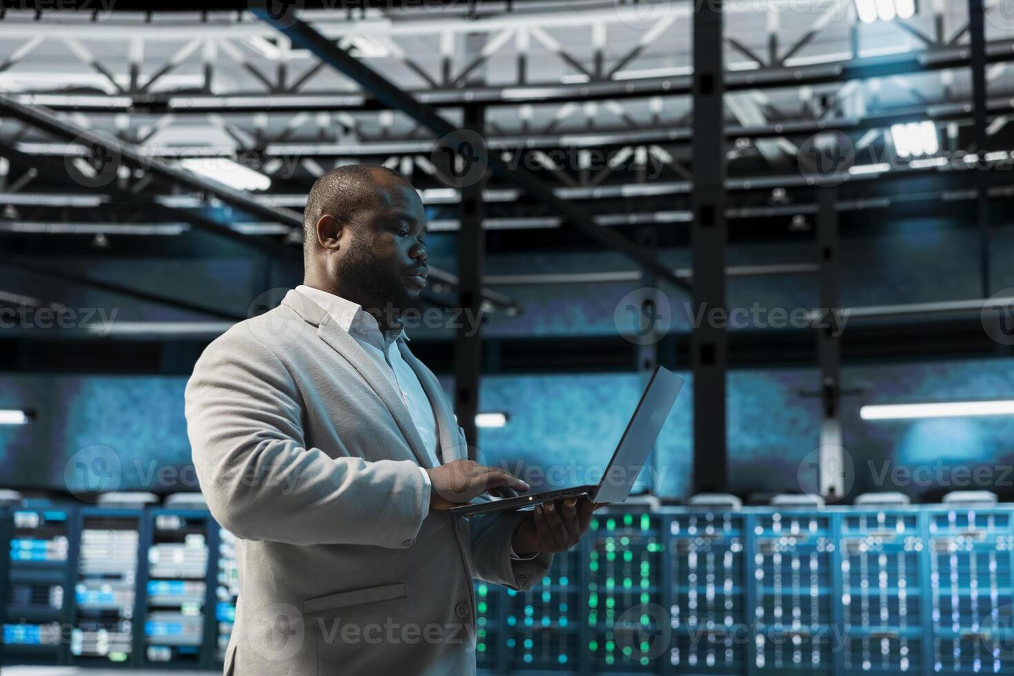 Data center admin runs system diagnostic tests, optimizing configurations. Server hub engineer using laptop to fix network issues affecting storage arrays, deploying tools to reduce downtime photo