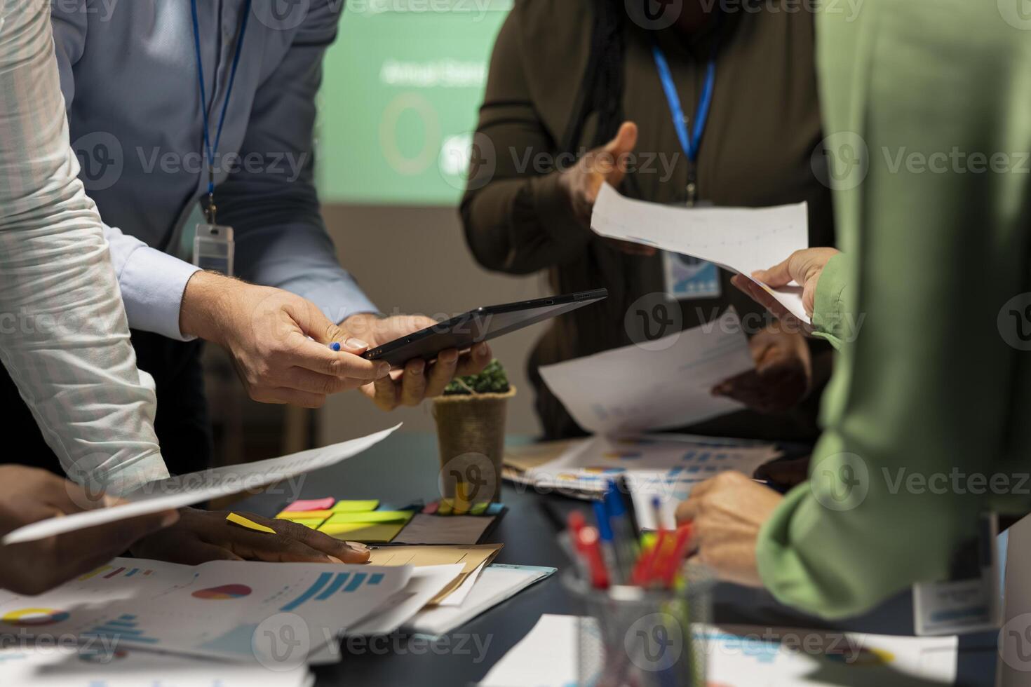 After hours briefing unfolds as a multiethnic group gathers in a strategy room, analyzing visual data, statistics and risk assessment files to drive project development forward for efficiency. photo