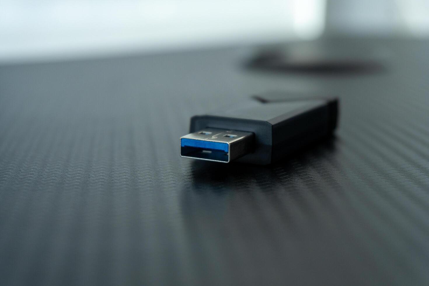 A USB flash drive is placed on a smooth black desktop surface, highlighting its design and utility in contemporary technology for storage and data transfer photo