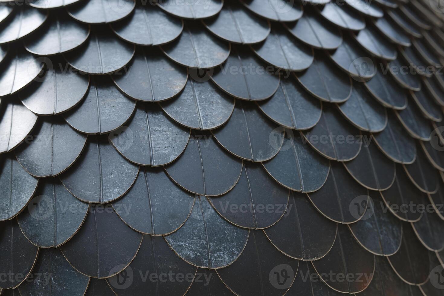 Close-up of textured metallic scales creating an artistic surface pattern with a dark finish. photo