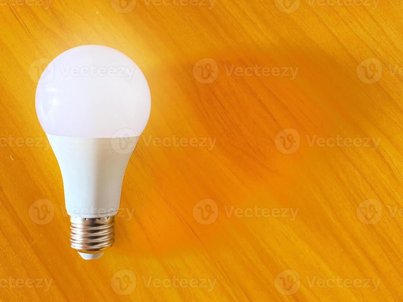 Energy efficient light bulb rests on a textured golden casting a soft glow photo