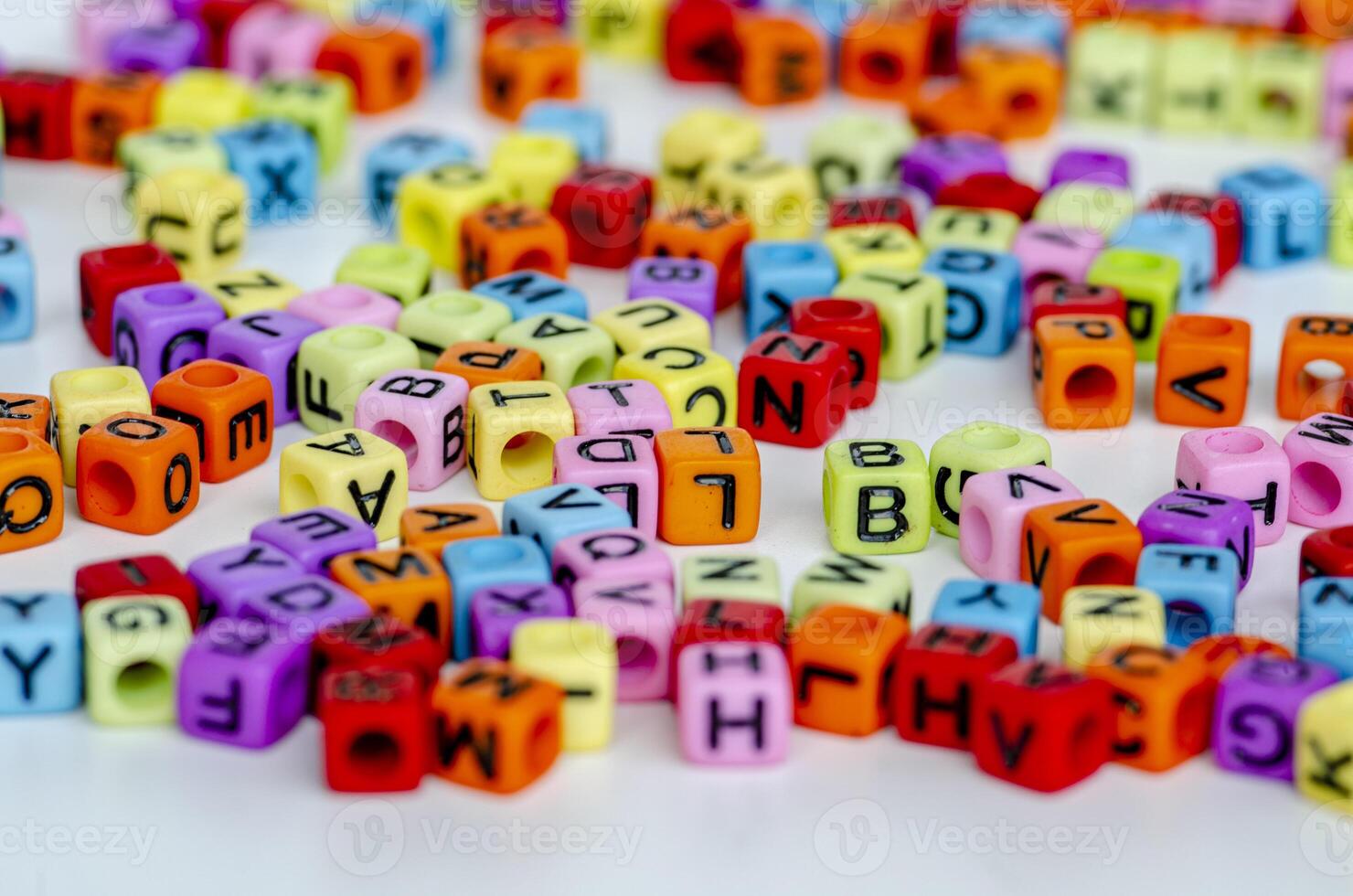 A focused display of glowing multicolored translucent cubes with black letters arranged messily on a clean white background reflecting fun and knowledge photo