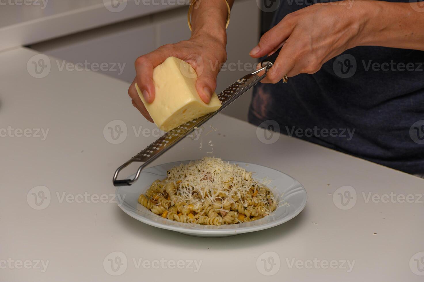 Female Home Cook Adding Cheese to Pasta photo