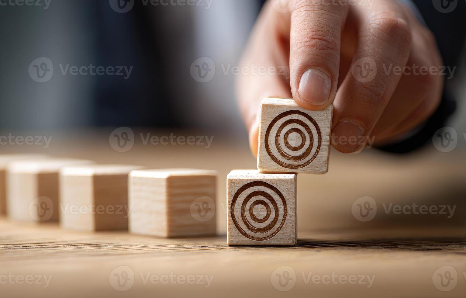 Hand placing a target-shaped wooden block onto a row of similar blocks photo