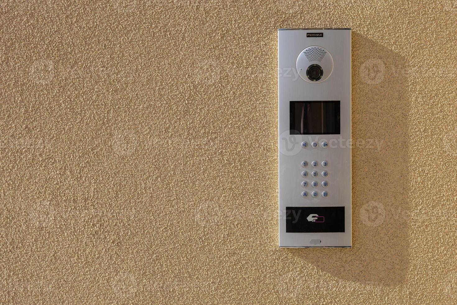Modern intercom system with camera, keypad and RFID access on textured wall in sunlight. Security technology for residential and commercial buildings, ensuring controlled access and communication photo