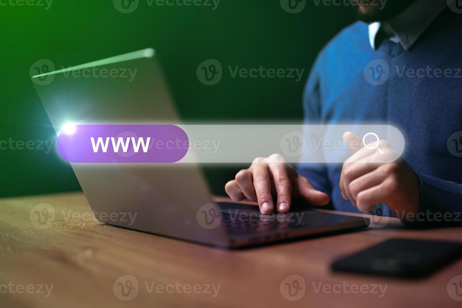 Man browsing the internet on laptop in an indoor setting during evening hours with a focus on search bar photo