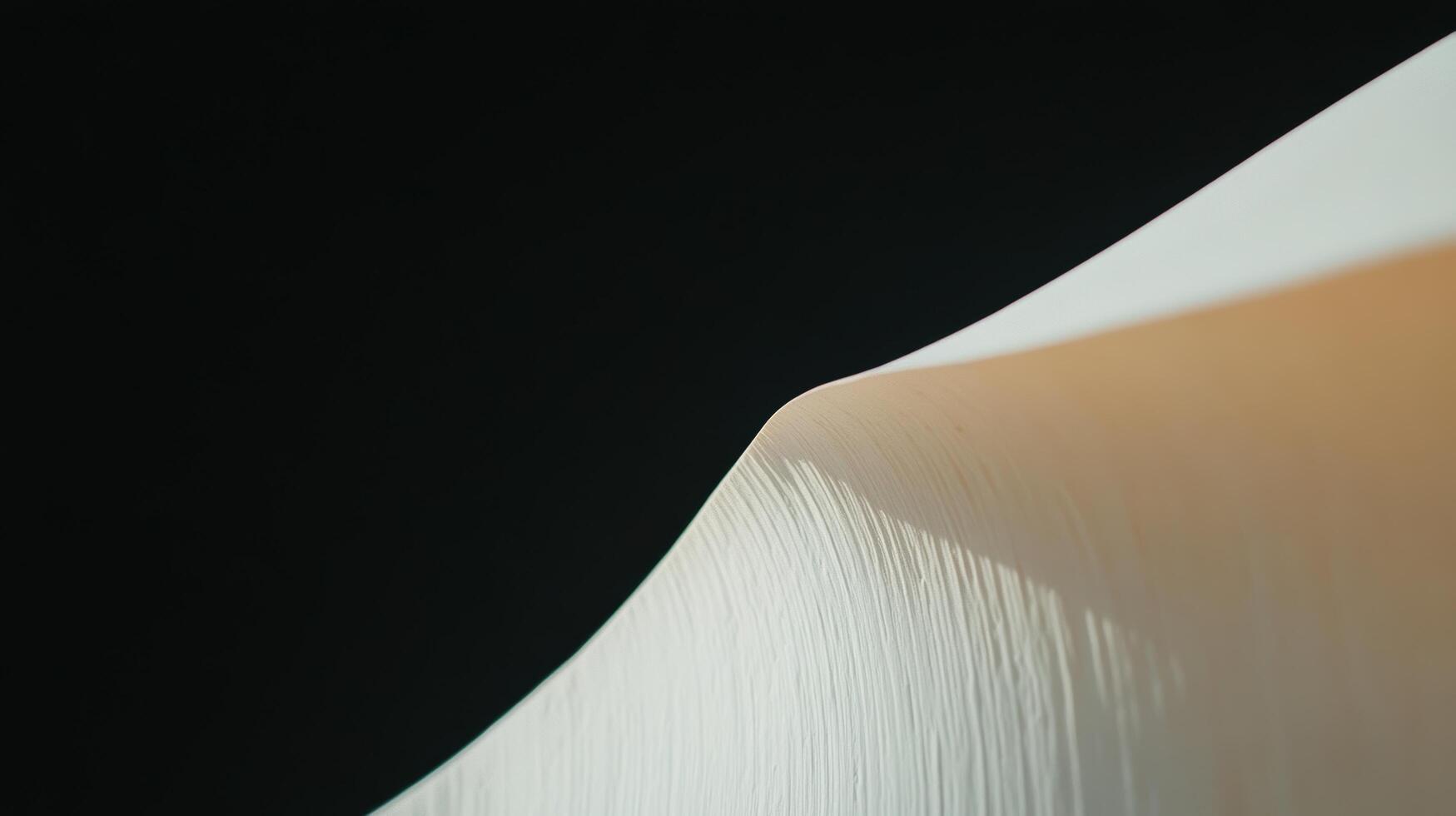Soft curves of a paper sheet against a dark background showcasing texture and light at midday photo