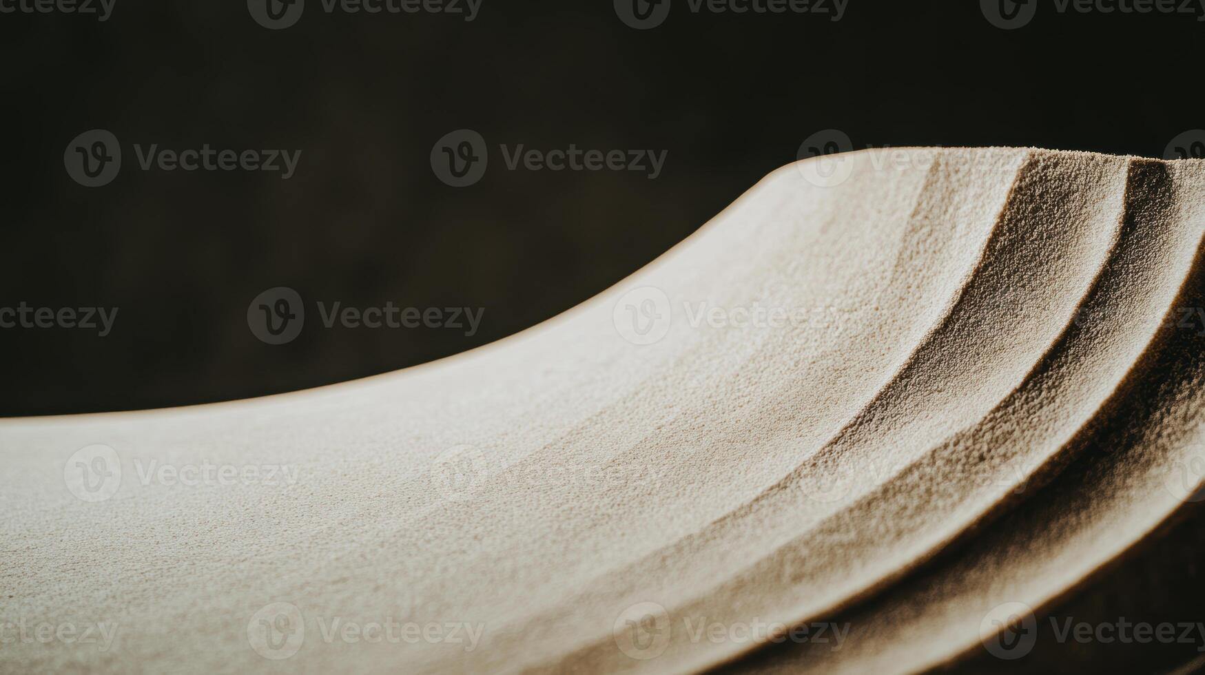 Textured surface displaying layers of smooth curves and gentle gradients in soft lighting photo