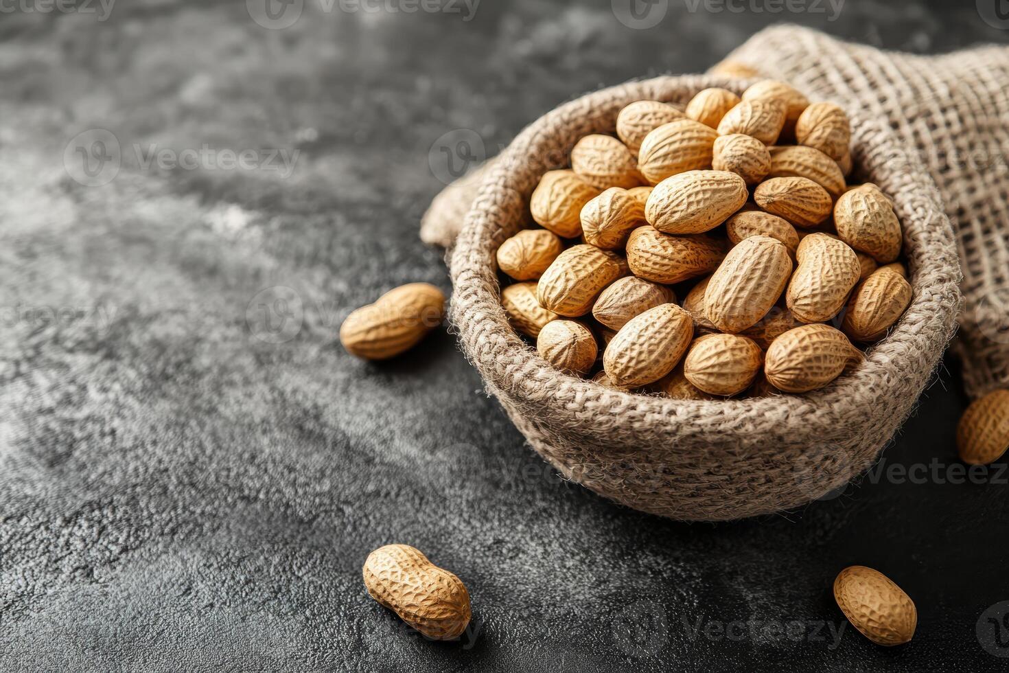 Peanuts in a burlap bowl on a textured dark background ready for snacking photo