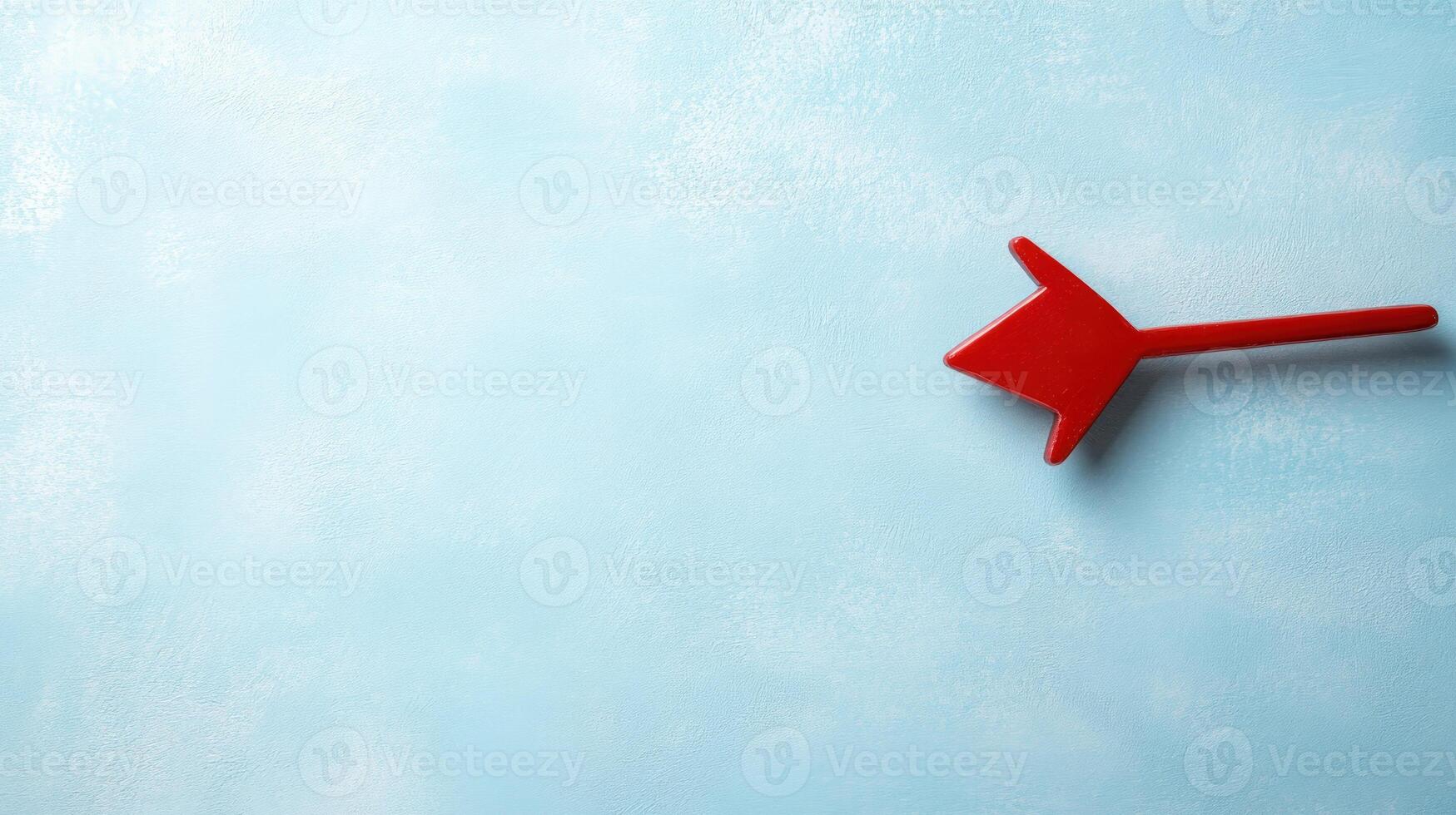 Red arrow pointing left on light blue textured background with empty copy space for text directional concept photo