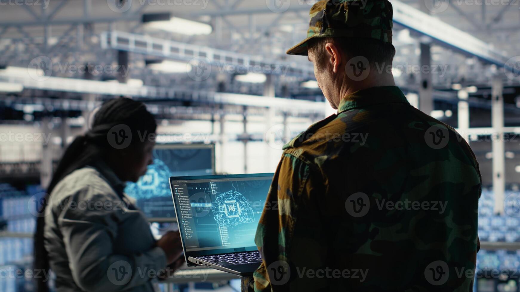 Soldier in engineering role uses AI application on laptop to manage server hub systems. Army commander reviews secret intelligence information using artificial intelligence in data center, camera B photo