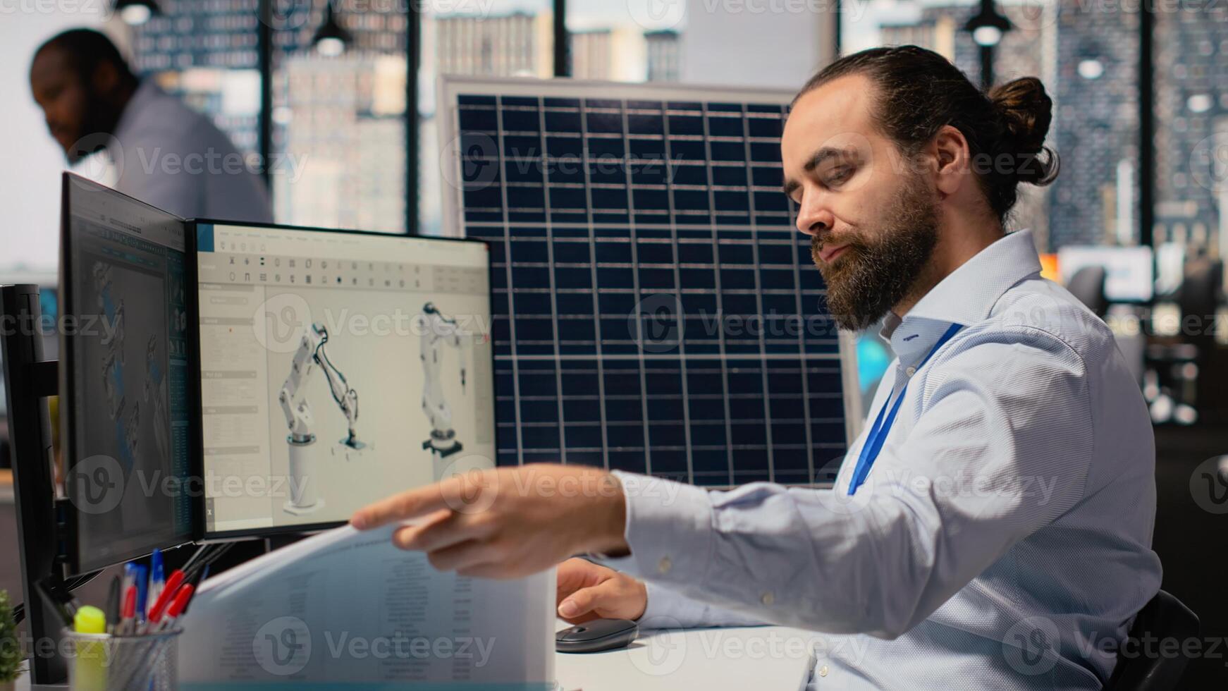 RD department researcher looking over documentation files to study solar green energy systems. Engineer using CAD software on PC to improve photovoltaics carbon footprint, camera B photo
