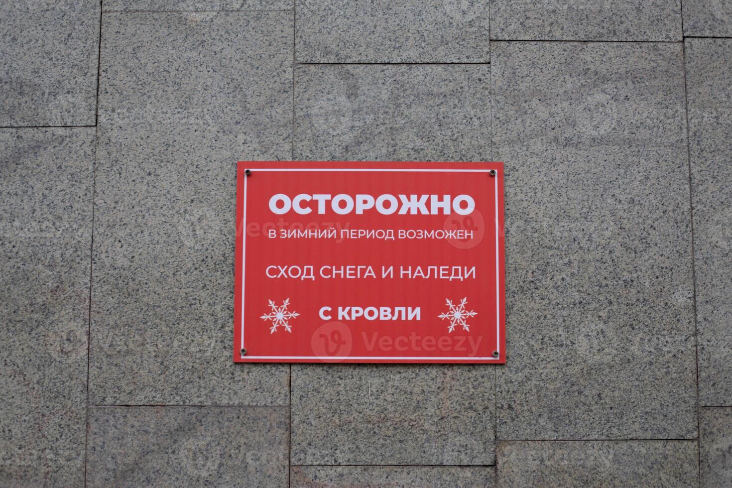 Taking care of citizens with warning sign. Sign in Russian stating possible danger of snow and ice falling from roof in public place. Do not go near building in winter to avoid snow falling from roof photo