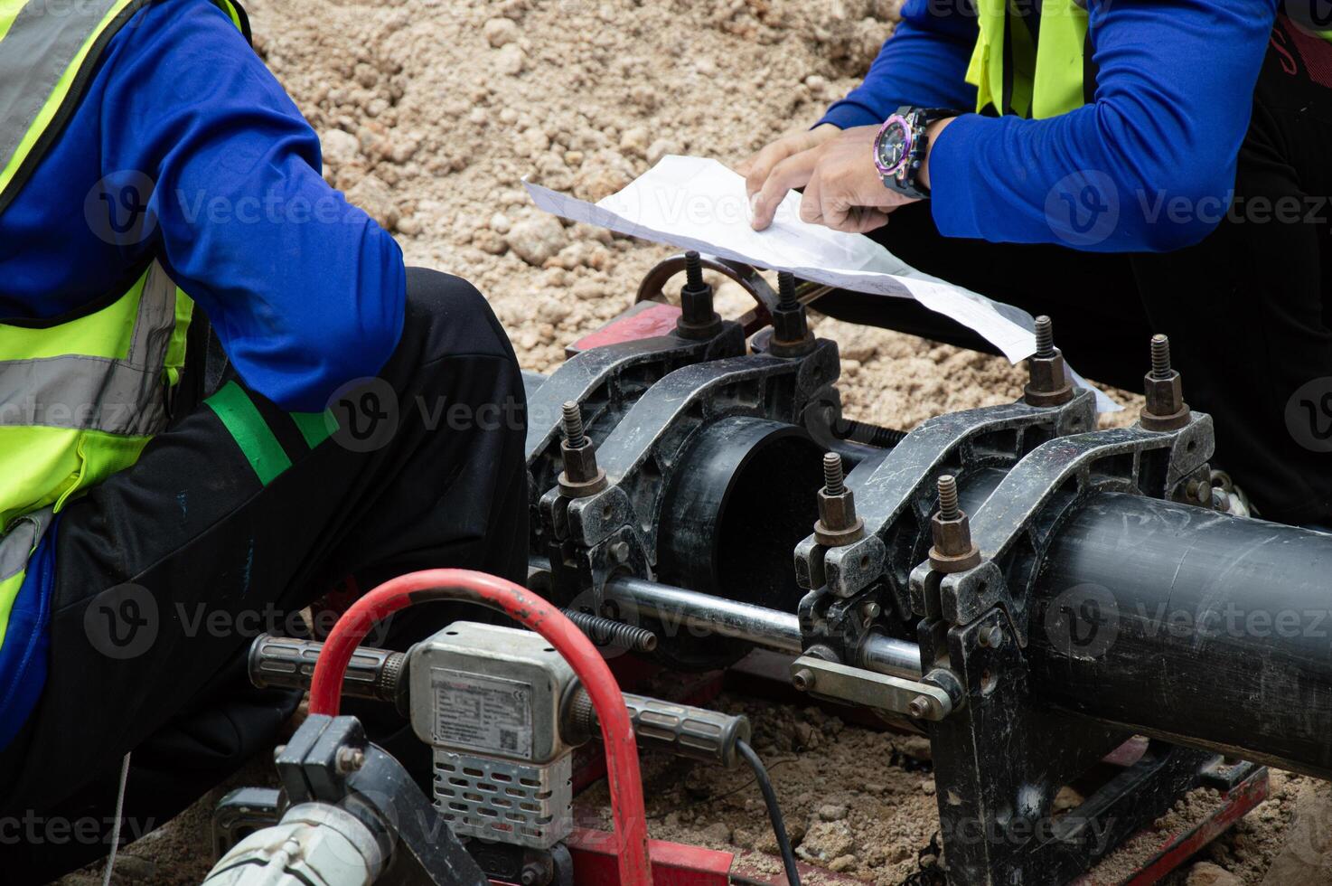 Engineers are looking at blueprints and using tools to connect pipes. photo