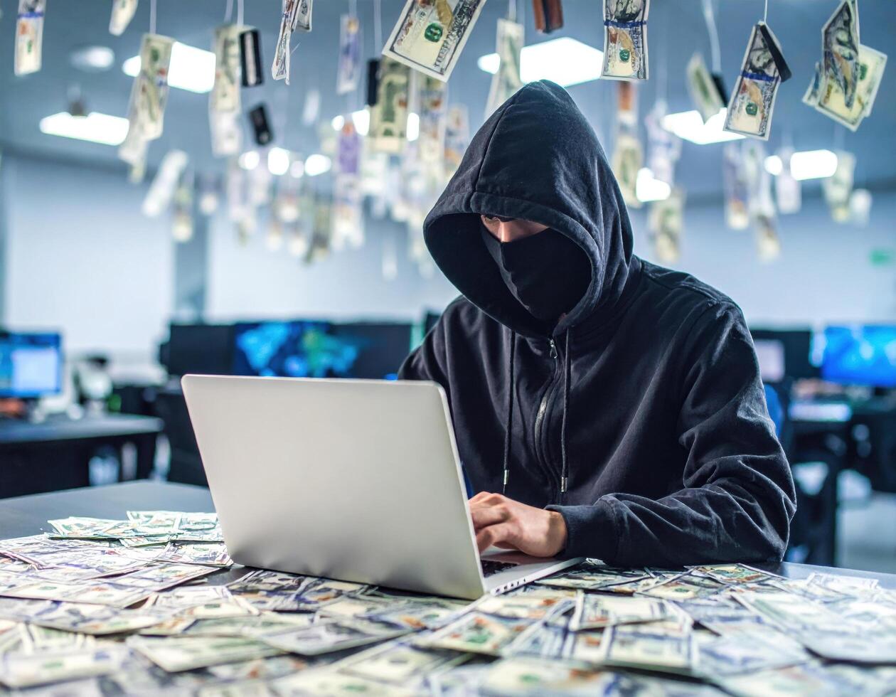 Hooded figure sits at laptop, surrounded by scattered money, creating mysterious and intense atmosphere. cool light from screen illuminates scene, emphasizing hacker focus and secrecy photo