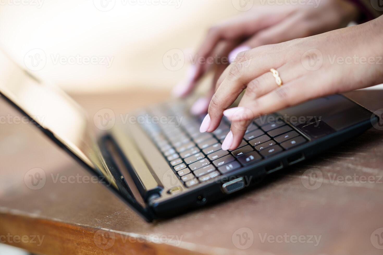 A Closeup Image of Hands Actively Typing on a Laptop Keyboard Within a Cozy Workspace Setting photo
