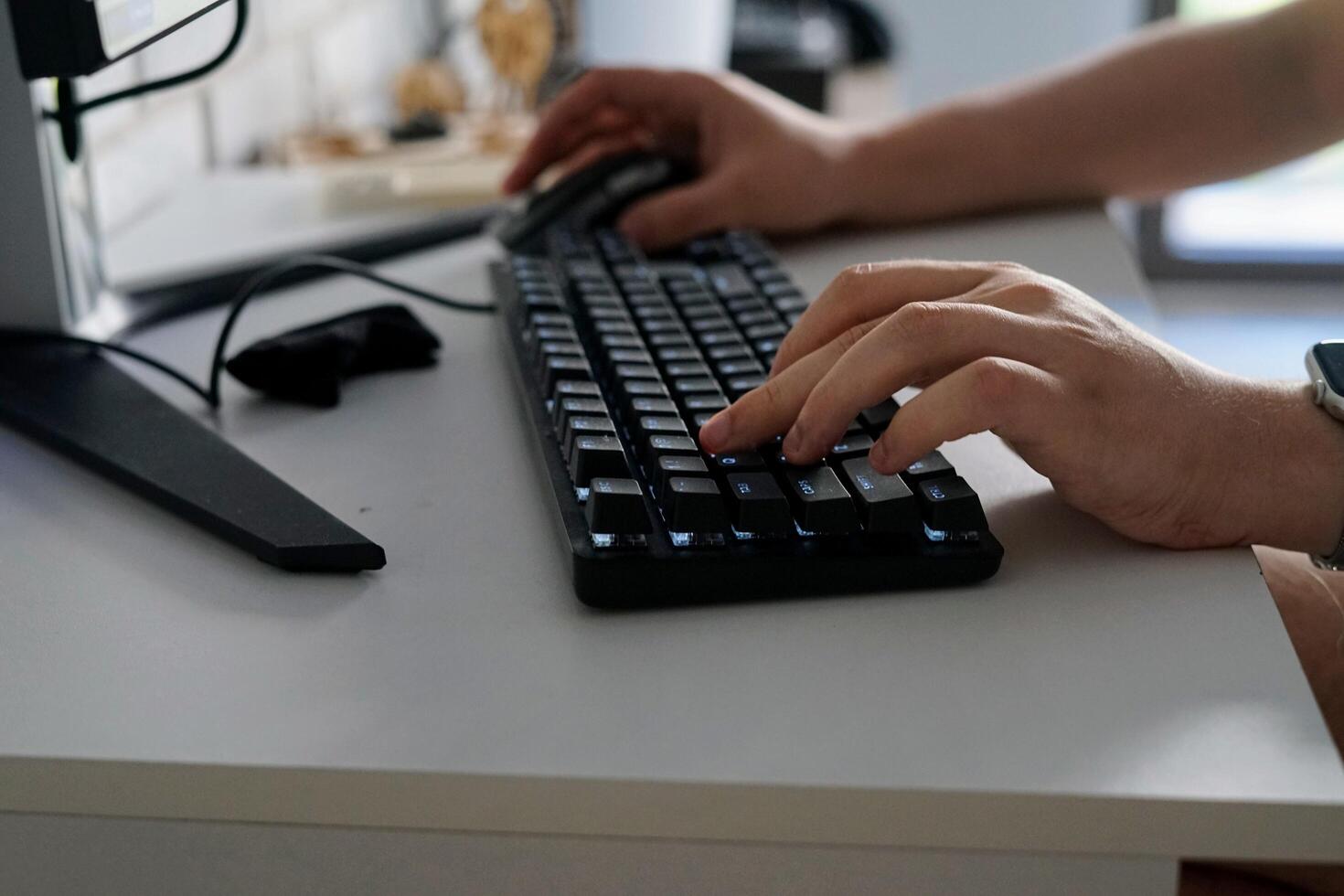 A Person man Engaged in Typing on a Computer Keyboard While at a Desk office work from home job busy doing remote play games photo