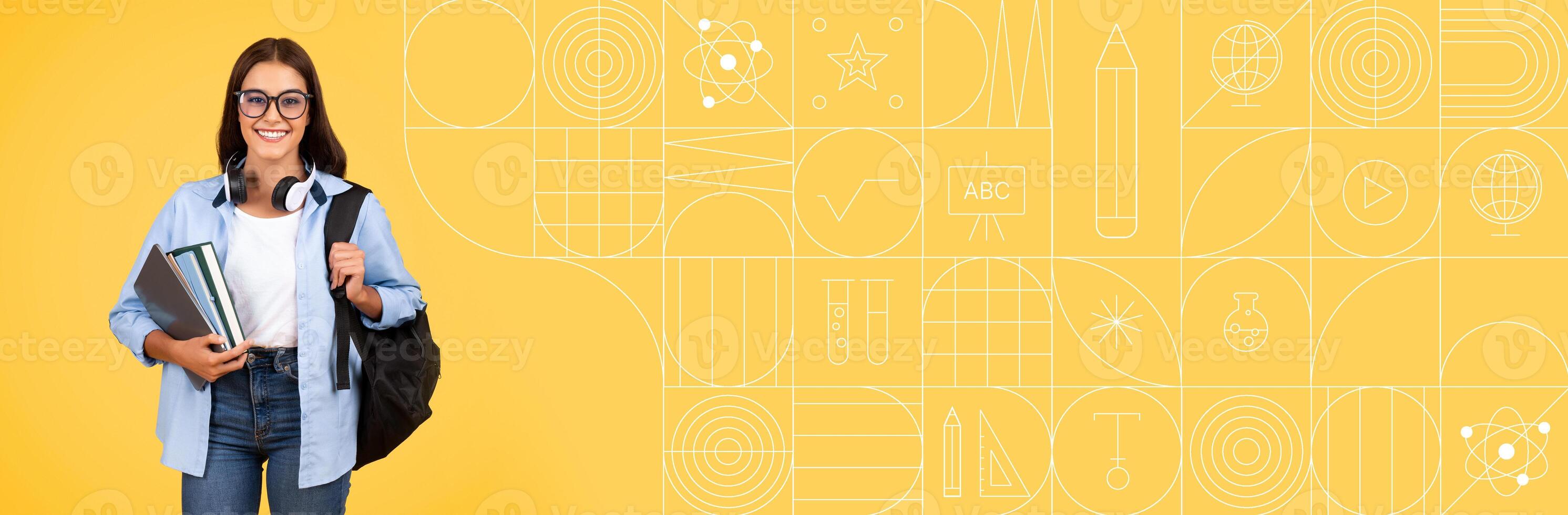 A student stands confidently with a backpack and books, smiling at the camera. The bright yellow background features educational graphics, creating an inviting atmosphere for learning. photo