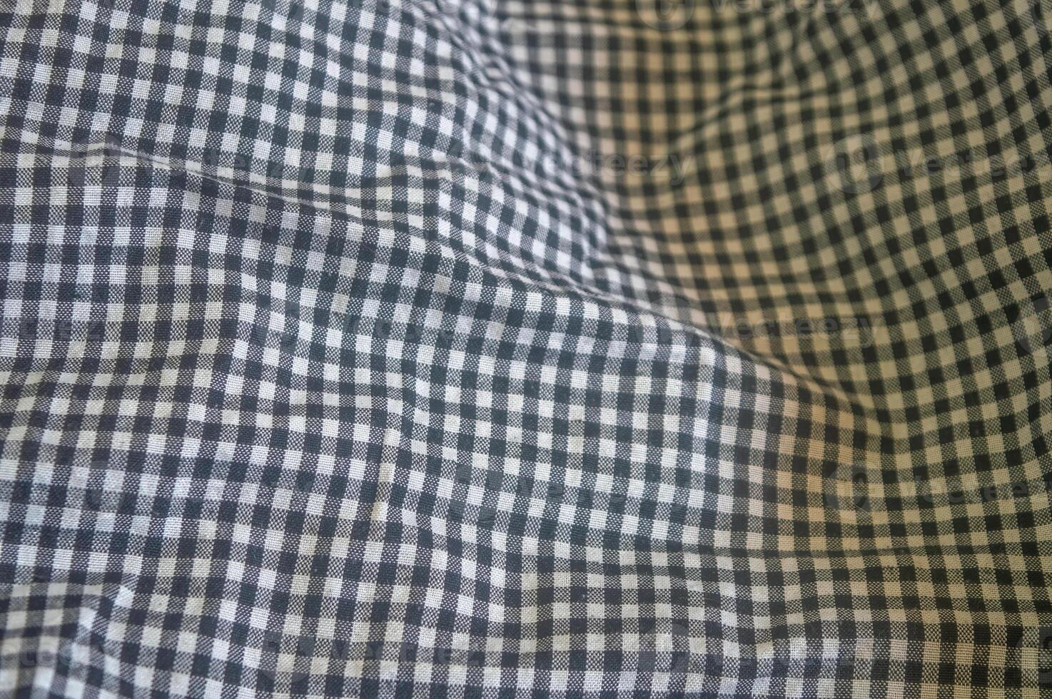 Close up on a black and white gingham fabric with a classic checkered pattern and soft folds, ideal for backgrounds, textiles, and designs with a touch of rustic charm photo