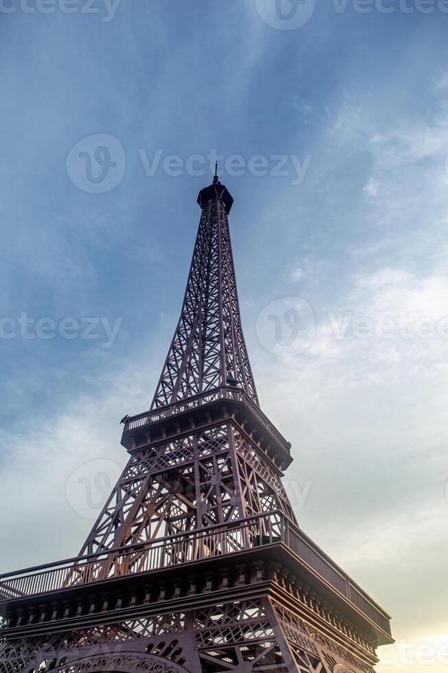 Eiffel tower against a blue sky with soft clouds, showcasing its intricate iron lattice structure and iconic silhouette, symbolizing travel and architectural achievement. photo