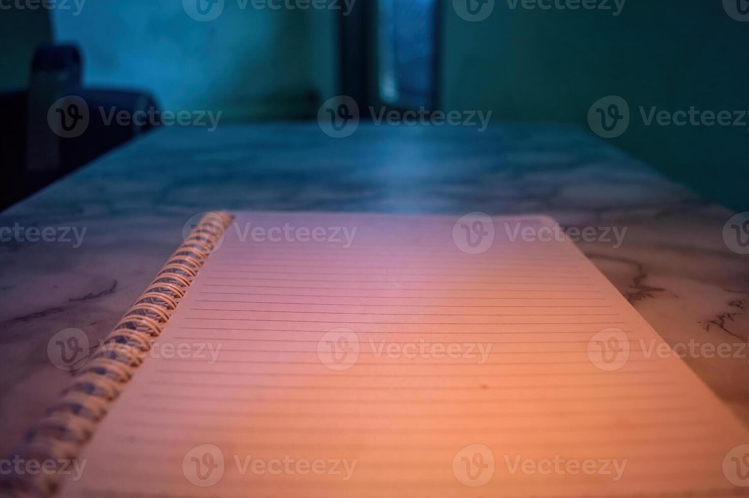 Close up of a spiral notebook with blank lined pages on a marble table. The notebook is closed, ready to be used for writing, note taking, or journaling, creating an opportunity for creativity photo